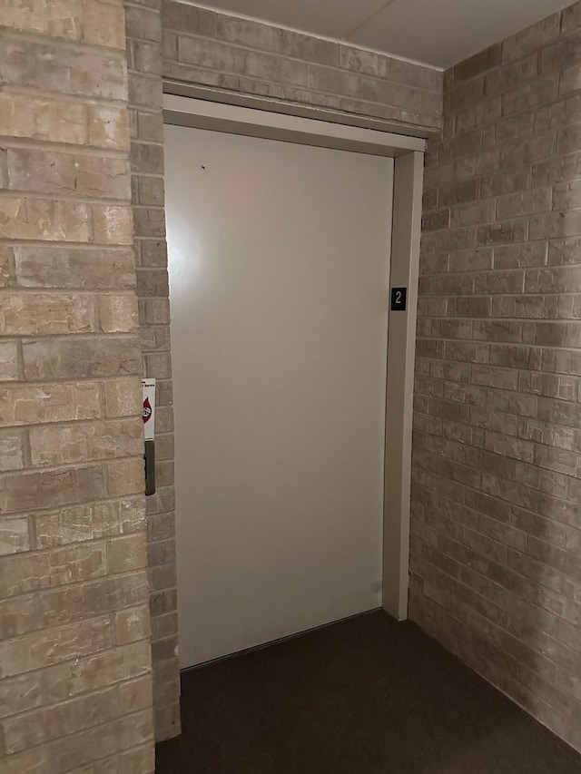 hallway with elevator and brick wall