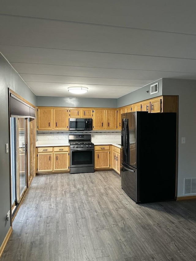 kitchen with tasteful backsplash, light wood-type flooring, and appliances with stainless steel finishes