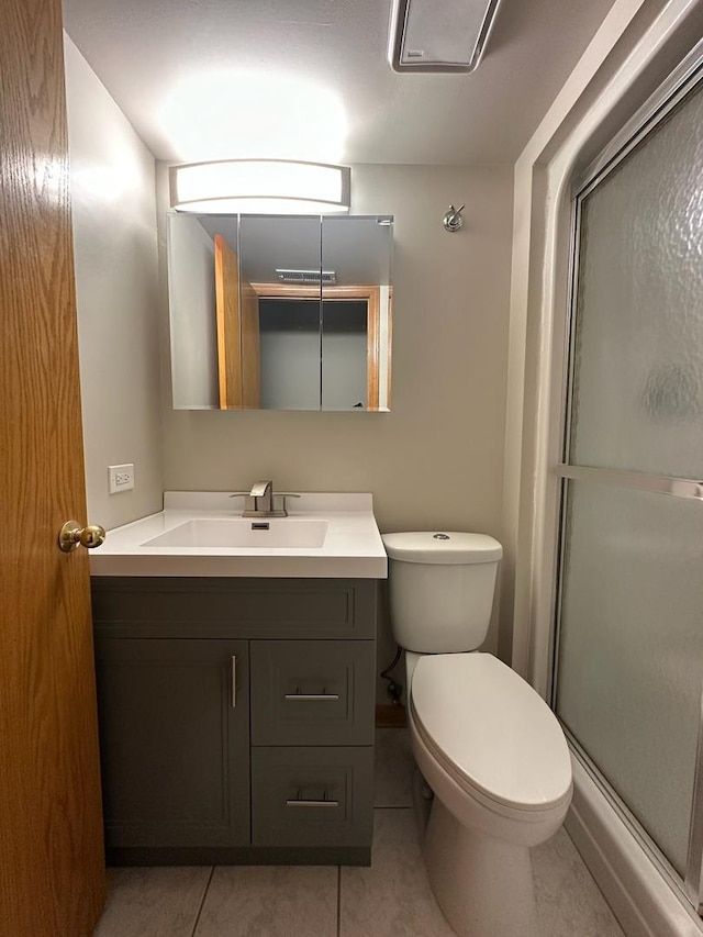 bathroom with toilet, tile patterned flooring, vanity, and walk in shower