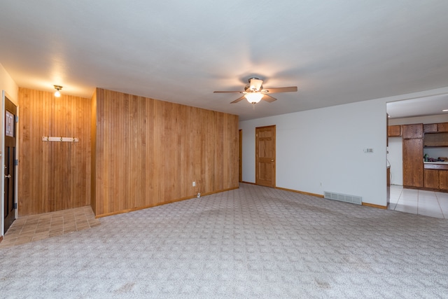 empty room with light carpet, ceiling fan, and wood walls