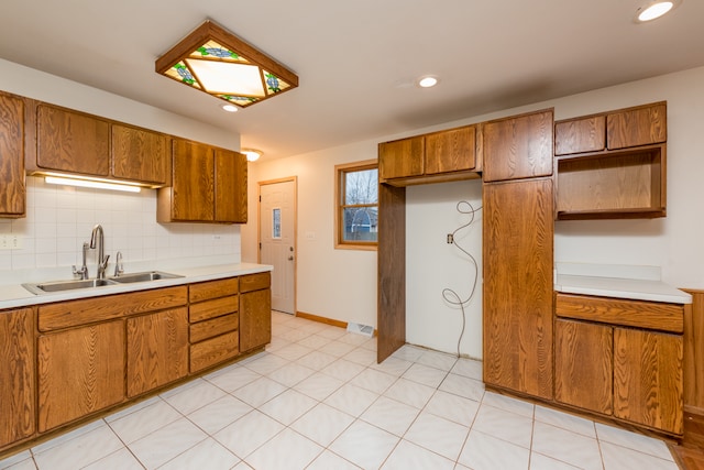 kitchen featuring backsplash, light tile patterned floors, and sink