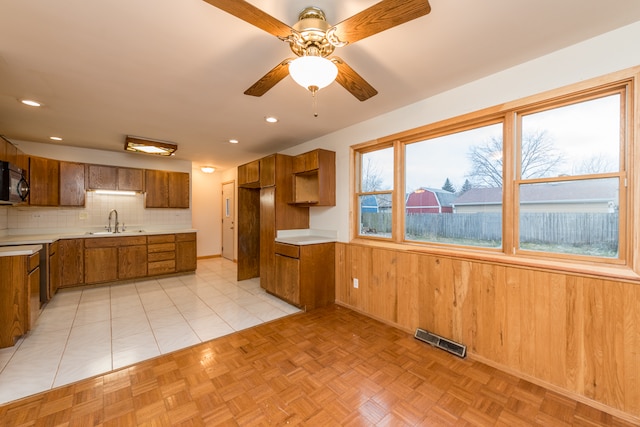 kitchen with ceiling fan, sink, wood walls, decorative backsplash, and light tile patterned floors