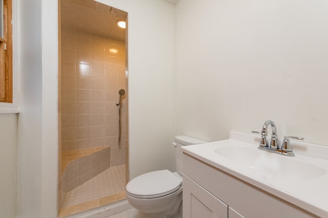 bathroom featuring a tile shower, vanity, and toilet