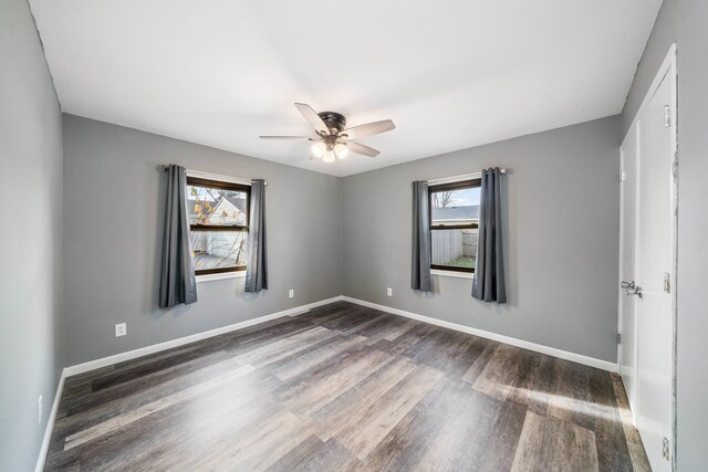 spare room featuring ceiling fan, a healthy amount of sunlight, and dark hardwood / wood-style floors