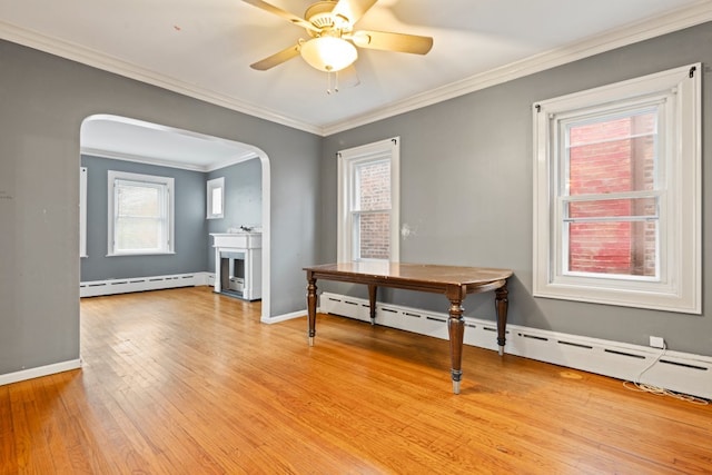 dining space featuring light wood-type flooring, a baseboard radiator, ceiling fan, and crown molding