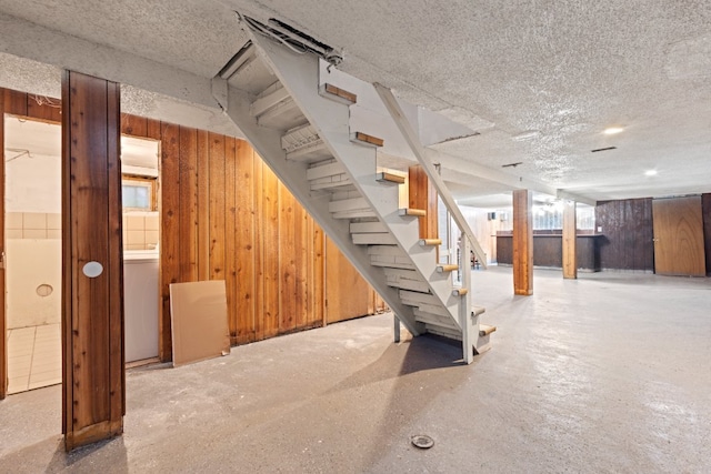 basement with a textured ceiling and wooden walls