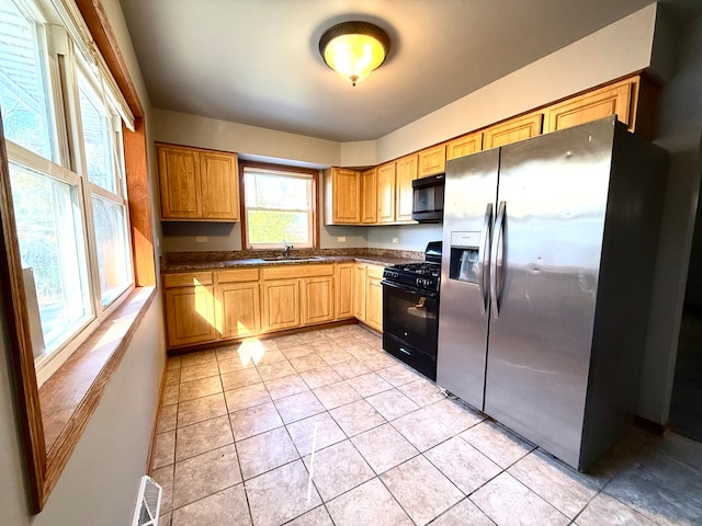 kitchen with black appliances, light tile patterned floors, and sink