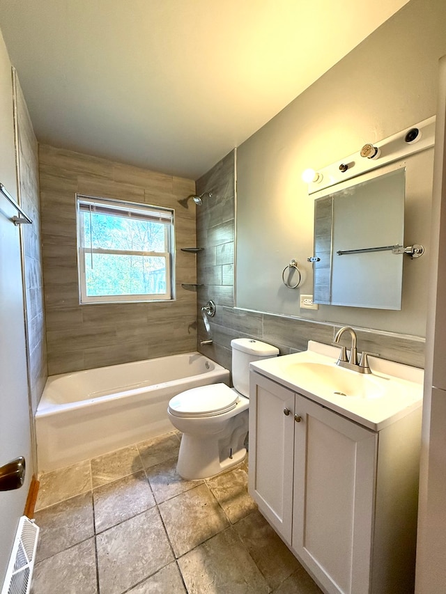 full bathroom featuring vanity, toilet, tile walls, and tiled shower / bath combo