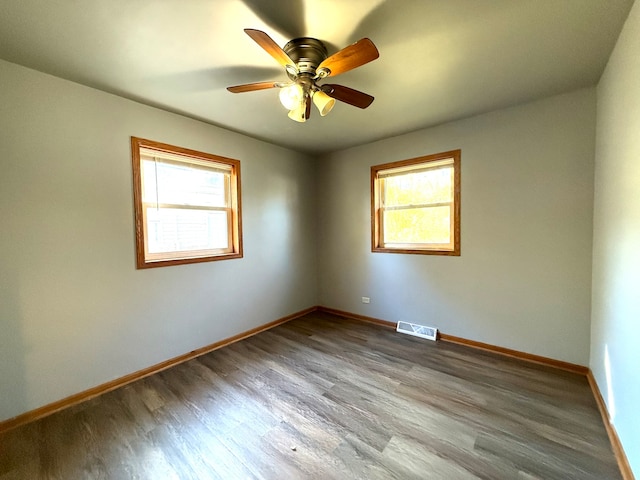 empty room featuring wood-type flooring, ceiling fan, and a healthy amount of sunlight