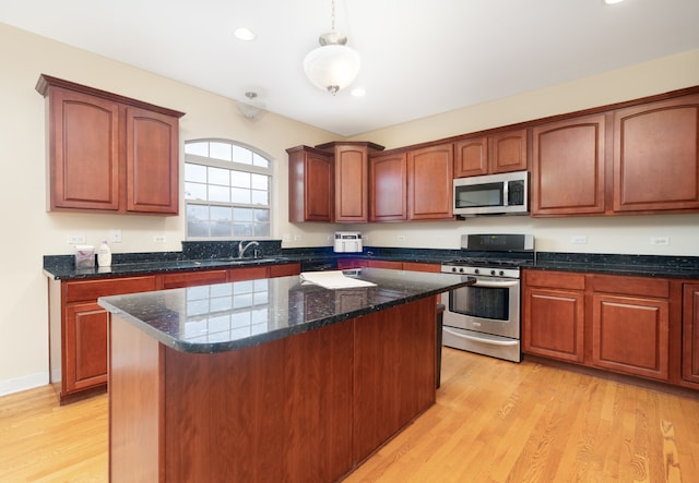 kitchen with decorative light fixtures, light wood-type flooring, stainless steel appliances, and a kitchen island