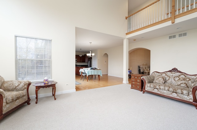 living room with light hardwood / wood-style flooring, a high ceiling, and a notable chandelier