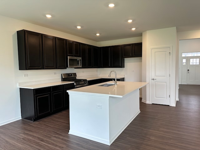 kitchen with sink, stainless steel appliances, an island with sink, and dark wood-type flooring