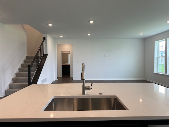 kitchen featuring light stone countertops, a kitchen island with sink, dark wood-type flooring, and sink