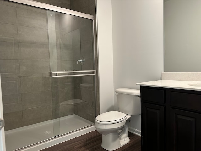 bathroom with hardwood / wood-style floors, vanity, toilet, and a shower with door