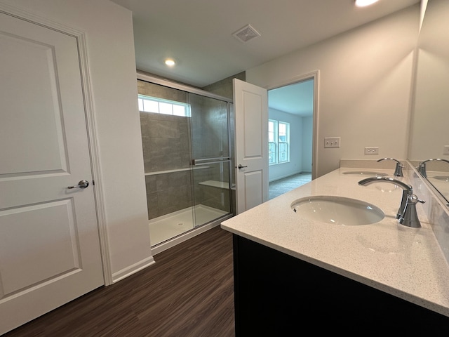 bathroom with wood-type flooring, a wealth of natural light, and a shower with shower door