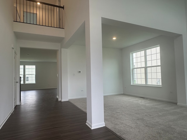 spare room with a high ceiling and dark colored carpet