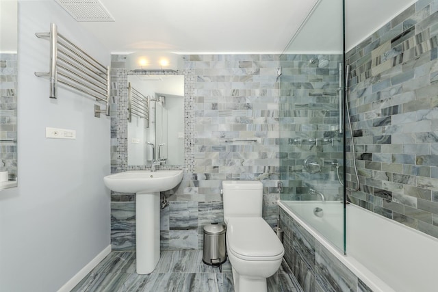 bathroom with tiled shower / bath, toilet, and tile walls