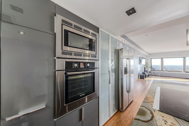 kitchen with stainless steel appliances, gray cabinetry, and light hardwood / wood-style flooring