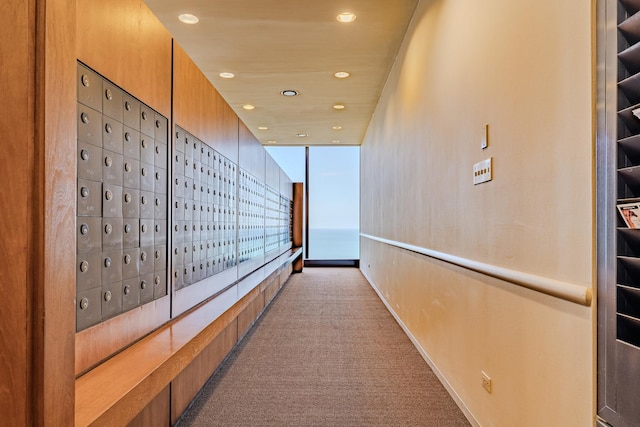 hall with light colored carpet, floor to ceiling windows, and a mail area