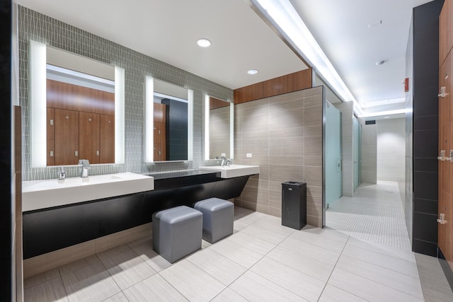 bathroom with a shower, tile patterned floors, tile walls, and vanity