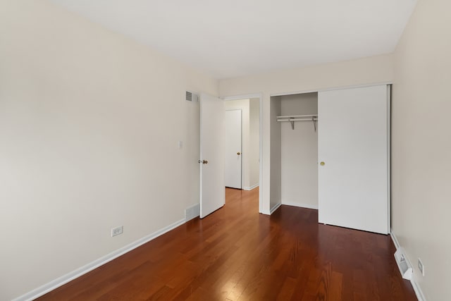 unfurnished bedroom with dark wood-type flooring and a closet