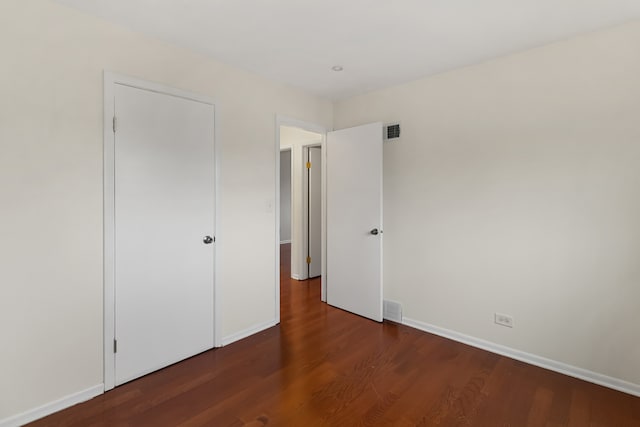 unfurnished bedroom featuring dark hardwood / wood-style flooring and a closet