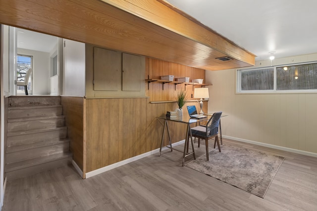 office space with light wood-type flooring and wooden walls