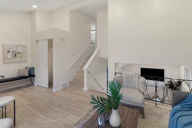 living room with light hardwood / wood-style flooring and a towering ceiling