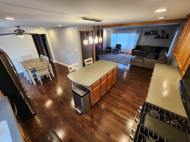 kitchen featuring ceiling fan, a kitchen island, pendant lighting, and dark hardwood / wood-style floors