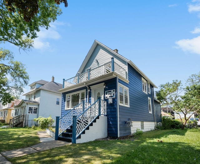 view of front of house with a balcony and a front lawn