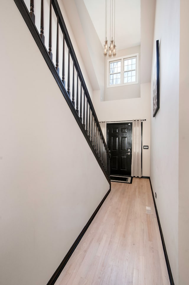 foyer featuring light hardwood / wood-style flooring, a towering ceiling, and a chandelier