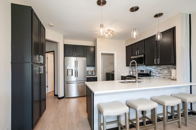 kitchen featuring pendant lighting, light hardwood / wood-style flooring, tasteful backsplash, kitchen peninsula, and stainless steel appliances