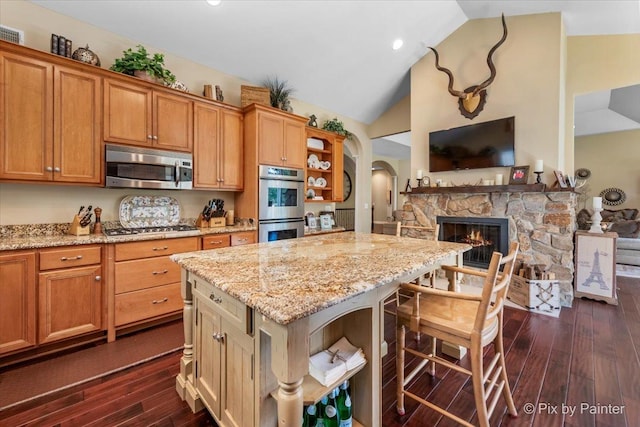 kitchen featuring a kitchen breakfast bar, stainless steel appliances, a center island, dark hardwood / wood-style floors, and lofted ceiling