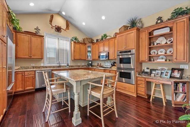 kitchen with a kitchen bar, light stone counters, stainless steel appliances, a center island, and dark hardwood / wood-style floors