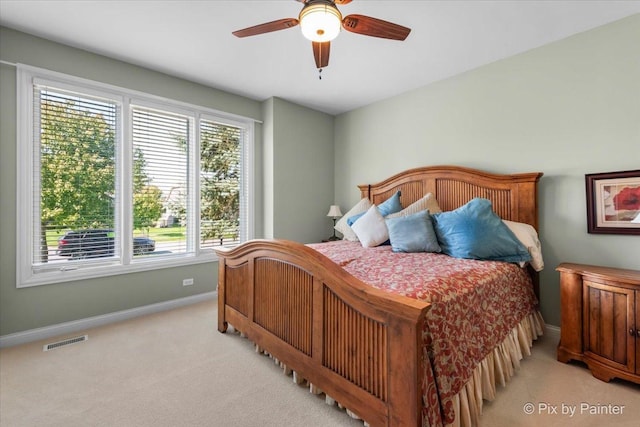 bedroom featuring multiple windows, light carpet, and ceiling fan