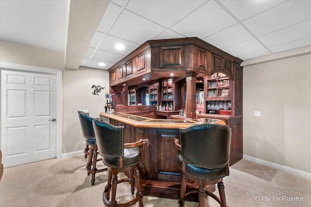 bar featuring a paneled ceiling and light colored carpet