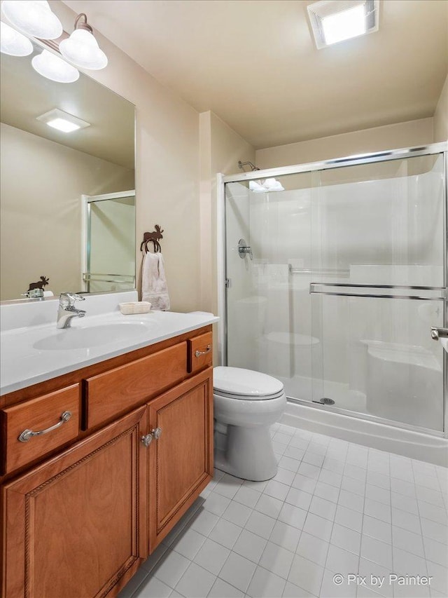 bathroom featuring tile patterned floors, walk in shower, vanity, and toilet