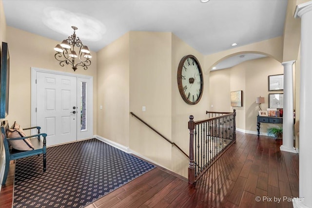 entryway with decorative columns, dark wood-type flooring, and a chandelier