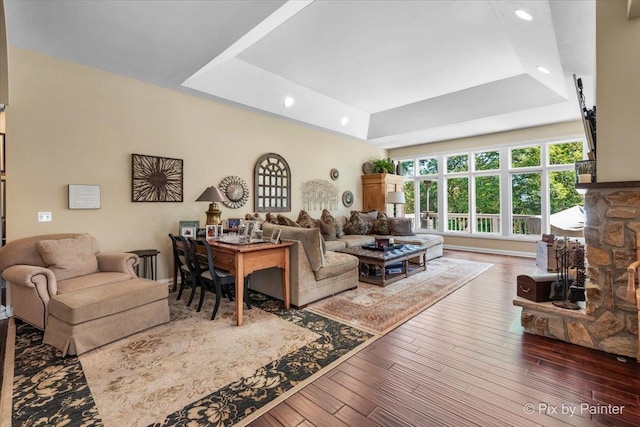 living room with hardwood / wood-style floors, a raised ceiling, and a fireplace