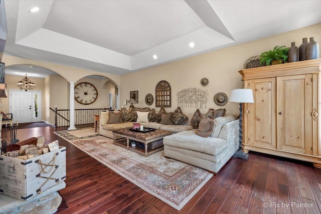 living room featuring a tray ceiling, dark hardwood / wood-style flooring, and an inviting chandelier