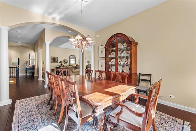 dining room with decorative columns, dark hardwood / wood-style floors, and an inviting chandelier