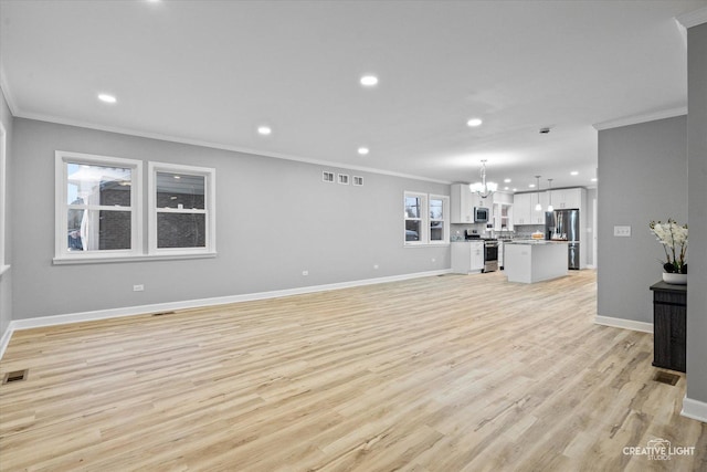 unfurnished living room with crown molding, light wood-type flooring, and a notable chandelier