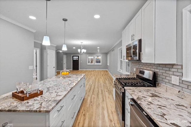 kitchen with white cabinets, decorative light fixtures, light stone counters, and stainless steel appliances