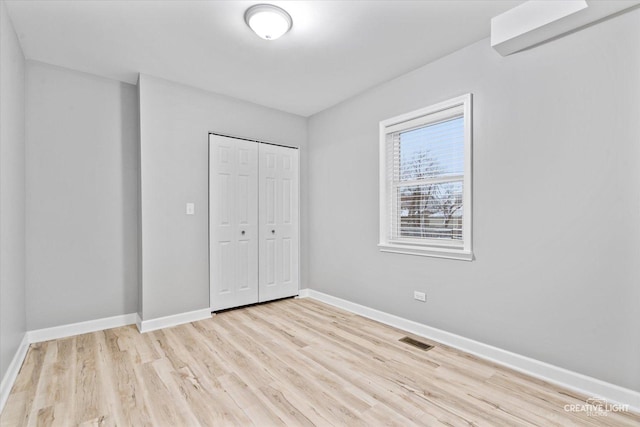 unfurnished bedroom with light hardwood / wood-style flooring and a closet