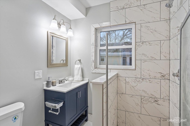 bathroom with toilet, a tile shower, and vanity