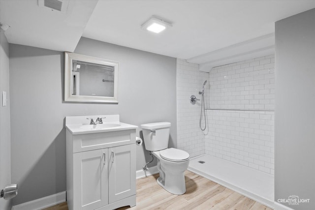 bathroom with tiled shower, hardwood / wood-style flooring, vanity, and toilet