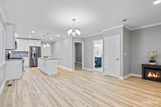 kitchen featuring hanging light fixtures, decorative backsplash, stainless steel fridge, a kitchen island, and white cabinetry