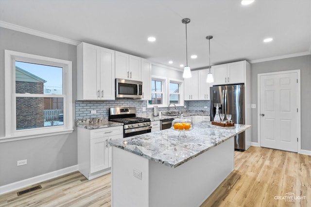 kitchen featuring white cabinetry, stainless steel appliances, tasteful backsplash, pendant lighting, and a kitchen island