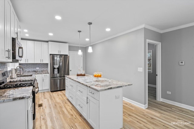 kitchen with white cabinetry, a kitchen island, pendant lighting, and appliances with stainless steel finishes