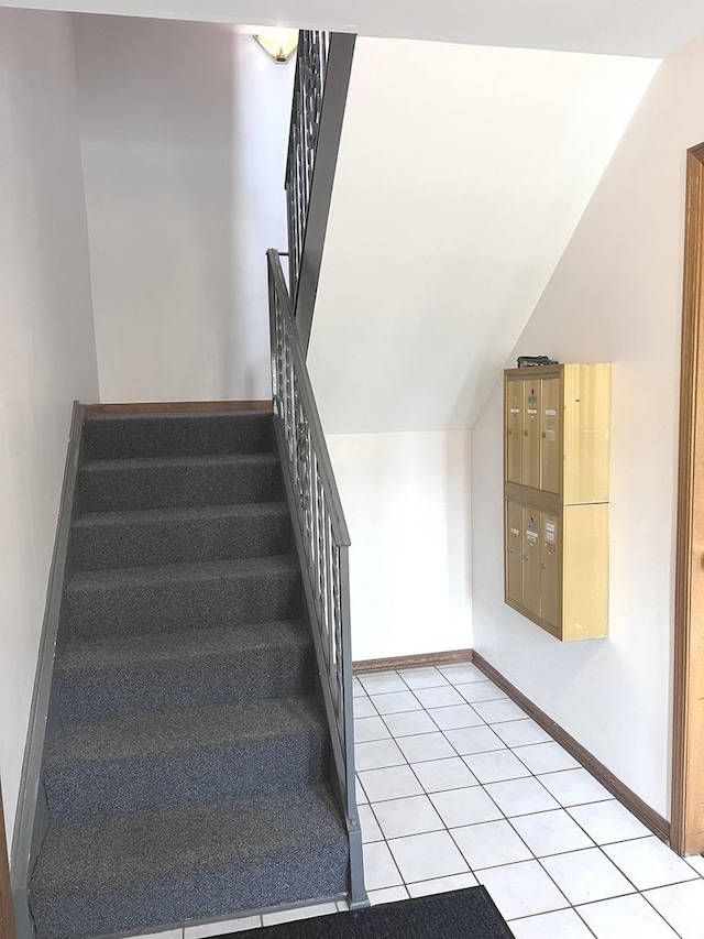 staircase with mail boxes, tile patterned flooring, and vaulted ceiling